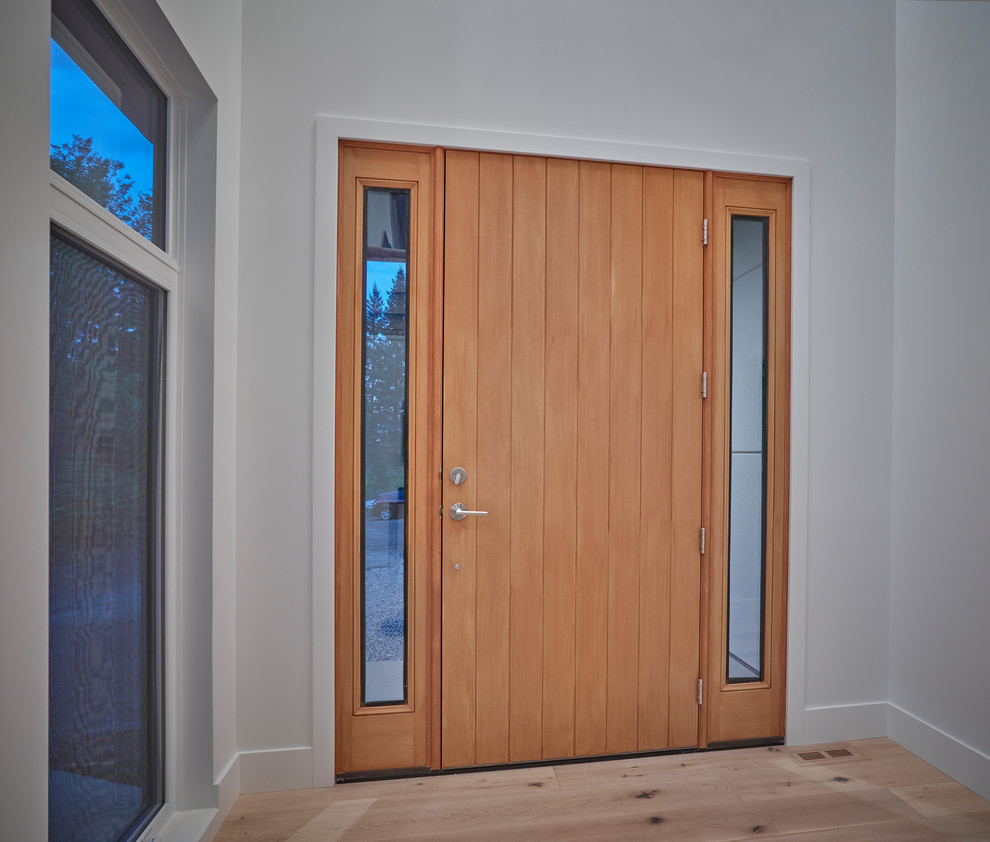 Modelo de puerta principal moderna de tamaño medio con paredes blancas, suelo de madera clara, puerta simple, puerta de madera clara y suelo beige