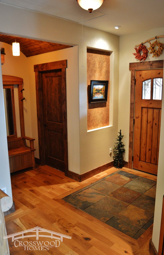 На фото: входная дверь среднего размера в стиле рустика с бежевыми стенами, полом из сланца, одностворчатой входной дверью и входной дверью из дерева среднего тона