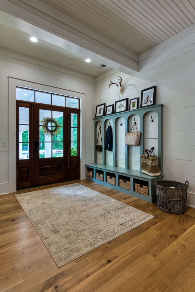 Immagine di una porta d'ingresso country di medie dimensioni con pareti bianche, pavimento in legno massello medio, una porta singola, una porta in legno bruno e pavimento marrone
