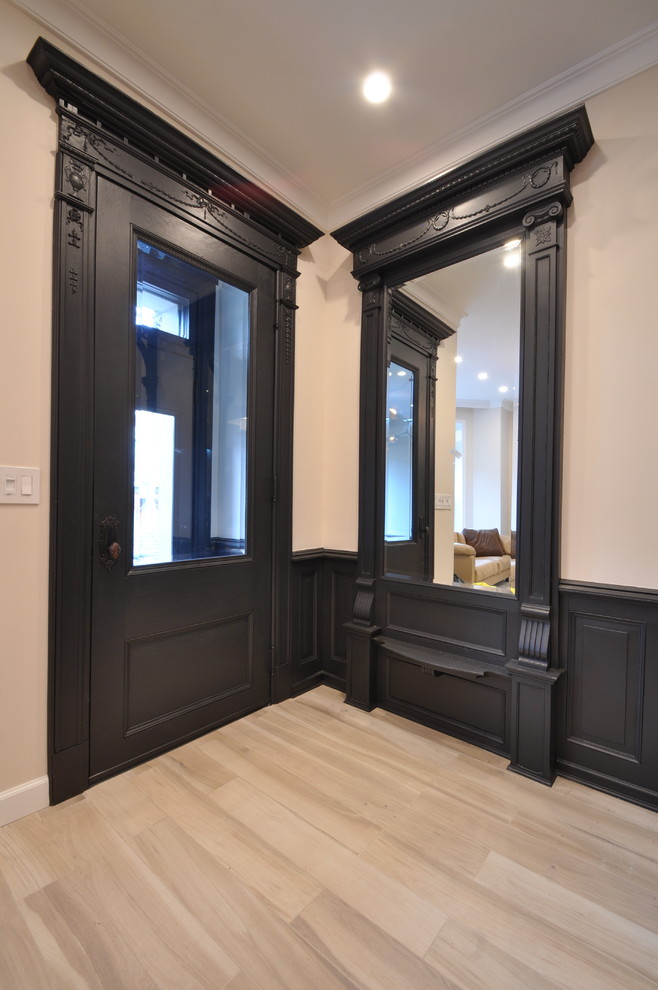 Diseño de puerta principal clásica pequeña con paredes beige, suelo de madera clara, puerta simple y puerta negra
