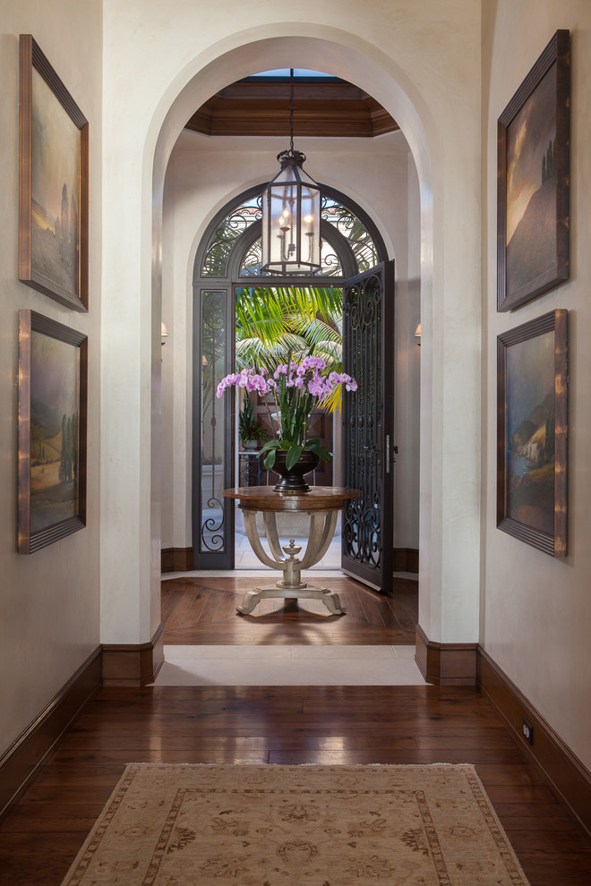 Mediterraner Eingang mit Korridor, braunem Holzboden, Einzeltür, Haustür aus Metall und weißer Wandfarbe in Orange County