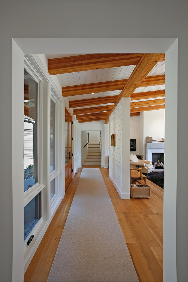 Modelo de entrada clásica renovada con paredes blancas, suelo de madera clara, puerta doble y puerta de madera clara
