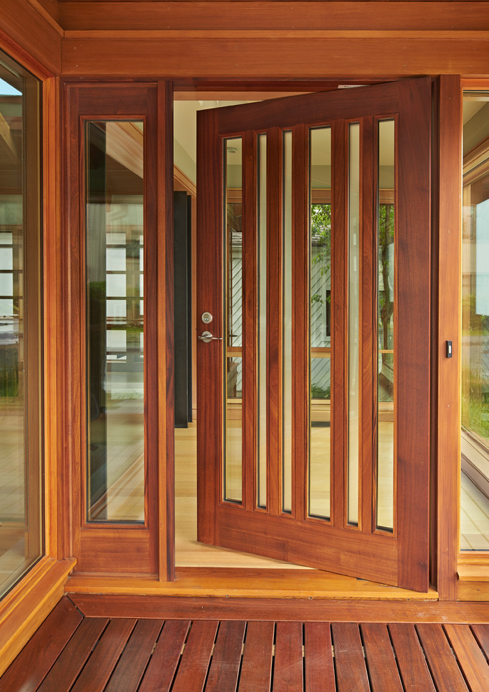 Réalisation d'une porte d'entrée design avec parquet clair, une porte simple et une porte en bois brun.