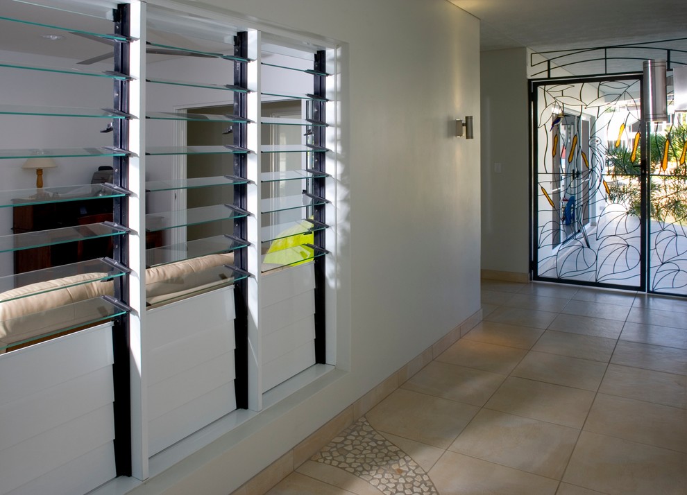 ダーウィンにある中くらいなトロピカルスタイルのおしゃれな玄関ロビー (白い壁、セラミックタイルの床、金属製ドア) の写真