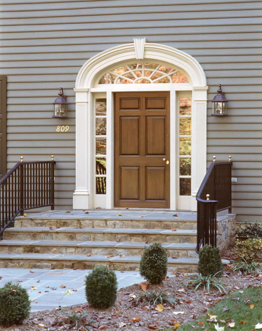 На фото: большая входная дверь в классическом стиле с серыми стенами, одностворчатой входной дверью и коричневой входной дверью