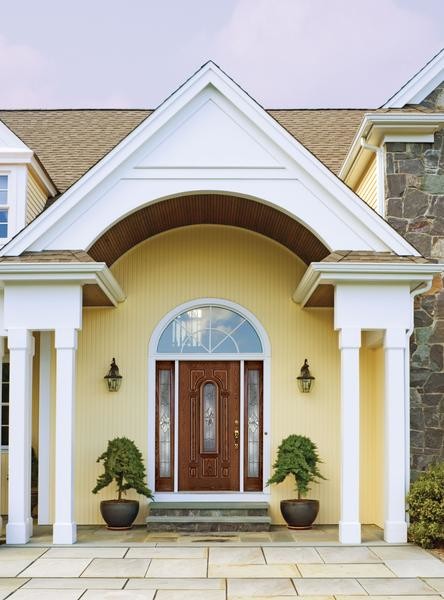 Пример оригинального дизайна: входная дверь среднего размера в стиле кантри с желтыми стенами, одностворчатой входной дверью и входной дверью из дерева среднего тона