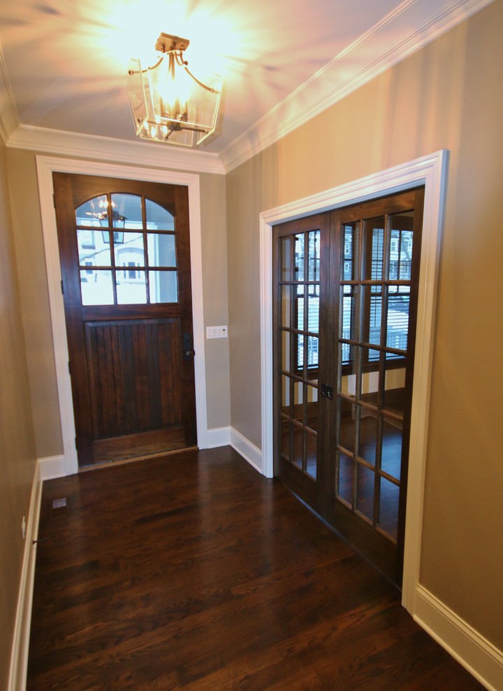 Immagine di una porta d'ingresso american style di medie dimensioni con pareti beige, pavimento in legno massello medio, una porta singola, una porta in legno bruno e pavimento marrone