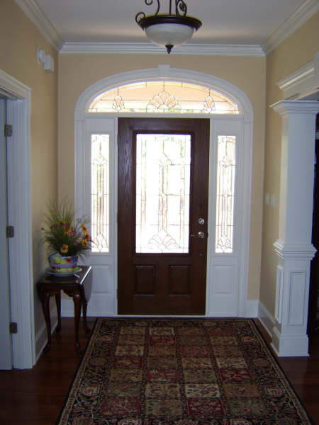 Mittelgroßes Klassisches Foyer mit gelber Wandfarbe, dunklem Holzboden, Einzeltür und dunkler Holzhaustür in Jackson