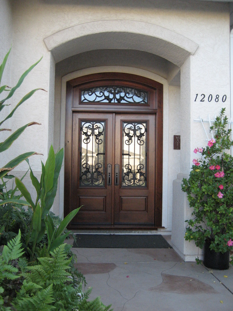 Diseño de puerta principal tradicional de tamaño medio con paredes blancas, suelo de travertino, puerta doble, puerta de madera oscura y suelo beige