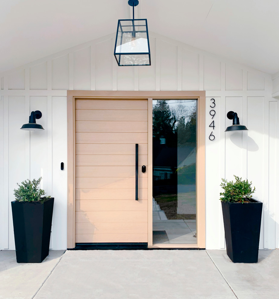 Diseño de puerta principal clásica renovada de tamaño medio con paredes blancas, suelo de cemento, puerta simple, puerta de madera clara y suelo blanco