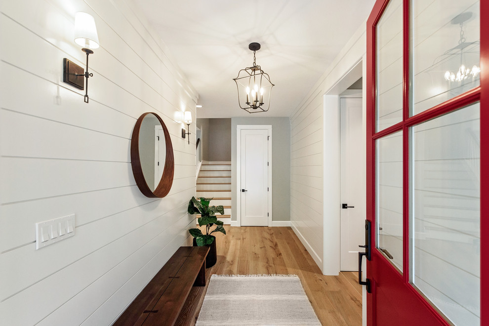 На фото: узкая прихожая в стиле кантри с белыми стенами, паркетным полом среднего тона, одностворчатой входной дверью, красной входной дверью и коричневым полом