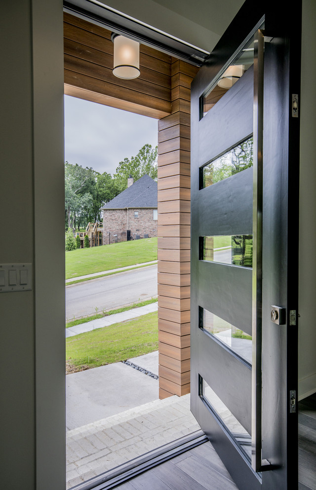 Esempio di una grande porta d'ingresso minimal con pareti bianche, pavimento in legno massello medio, una porta singola, una porta nera e pavimento grigio