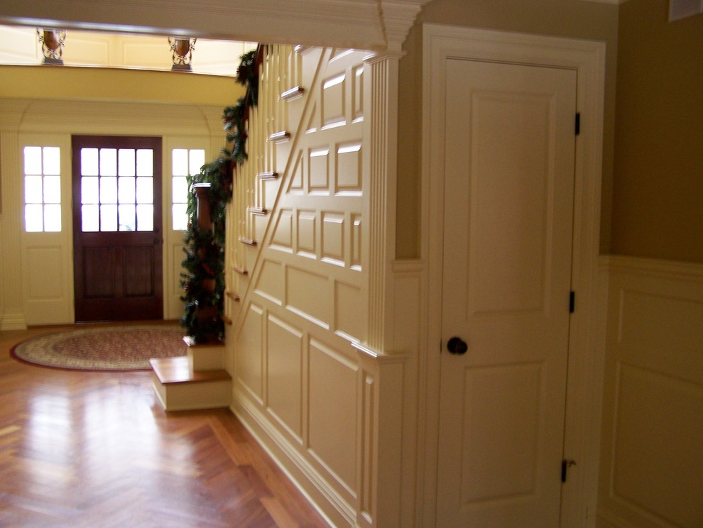 Immagine di un grande ingresso classico con pareti beige, pavimento in legno massello medio, una porta singola e una porta in legno scuro