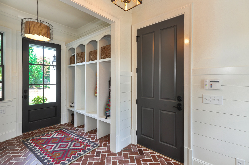 Пример оригинального дизайна: фойе в современном стиле с белыми стенами, кирпичным полом, одностворчатой входной дверью, серой входной дверью и красным полом