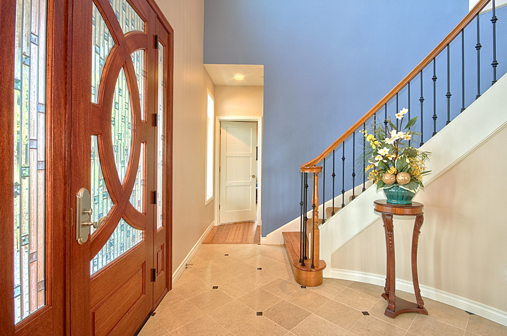 Ejemplo de distribuidor tradicional renovado pequeño con paredes azules, suelo de baldosas de porcelana, puerta simple, puerta de madera en tonos medios y suelo beige