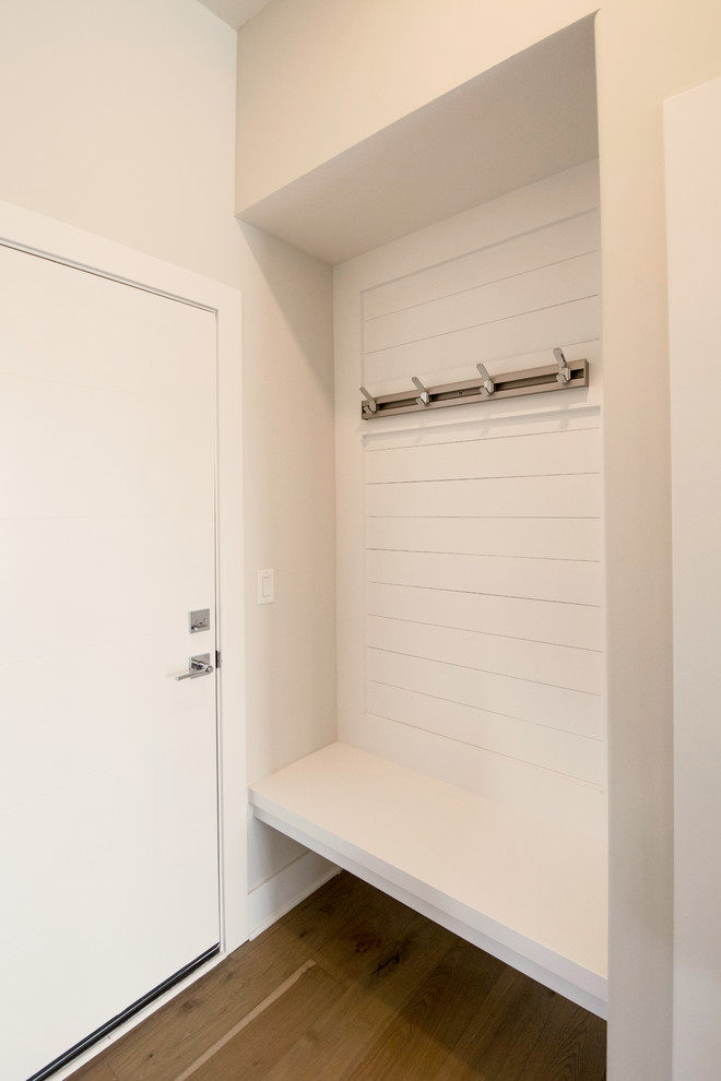 Photo of a small modern boot room in Wichita with beige walls, medium hardwood flooring, a single front door, a white front door and brown floors.