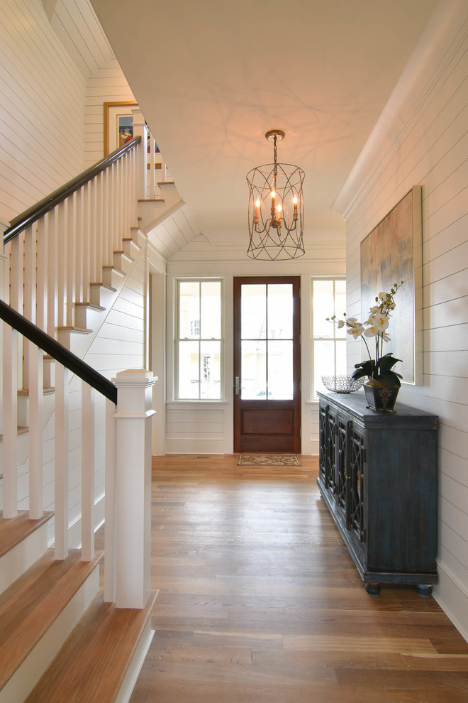 Example of a mid-sized classic medium tone wood floor and beige floor entryway design in Charleston with white walls and a glass front door