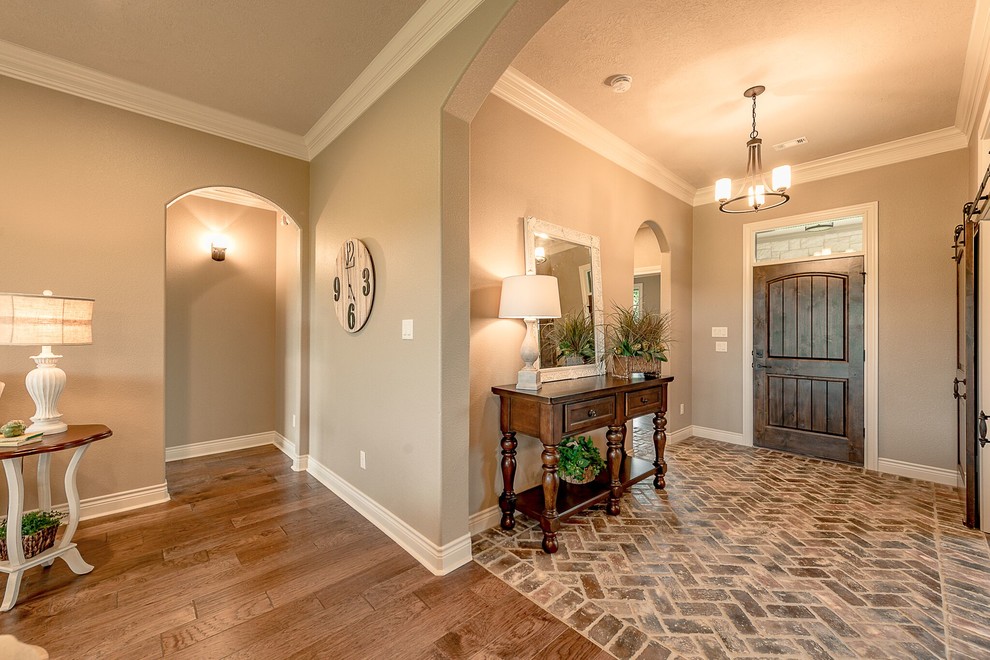 Mittelgroßes Uriges Foyer mit beiger Wandfarbe, braunem Holzboden, Einzeltür, hellbrauner Holzhaustür und braunem Boden in Austin