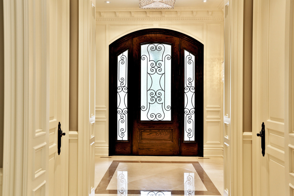 Idée de décoration pour une entrée tradition avec un mur beige, un sol en marbre, une porte simple et une porte en bois brun.