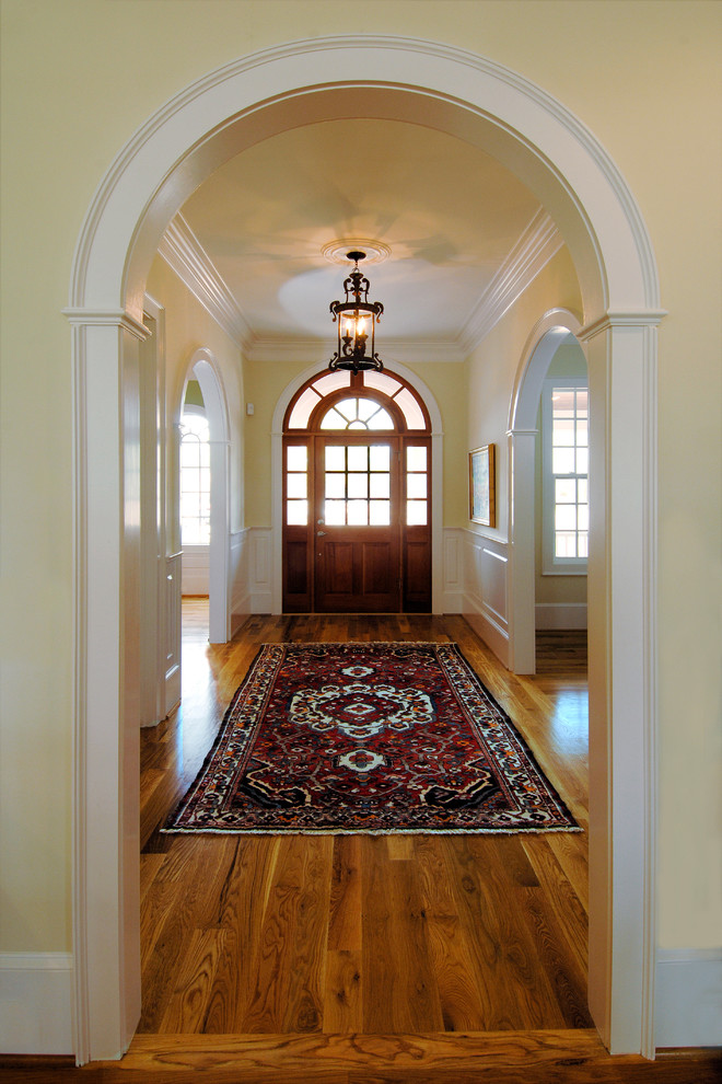 Mittelgroßes Klassisches Foyer mit gelber Wandfarbe, braunem Holzboden, Einzeltür und hellbrauner Holzhaustür in Sonstige