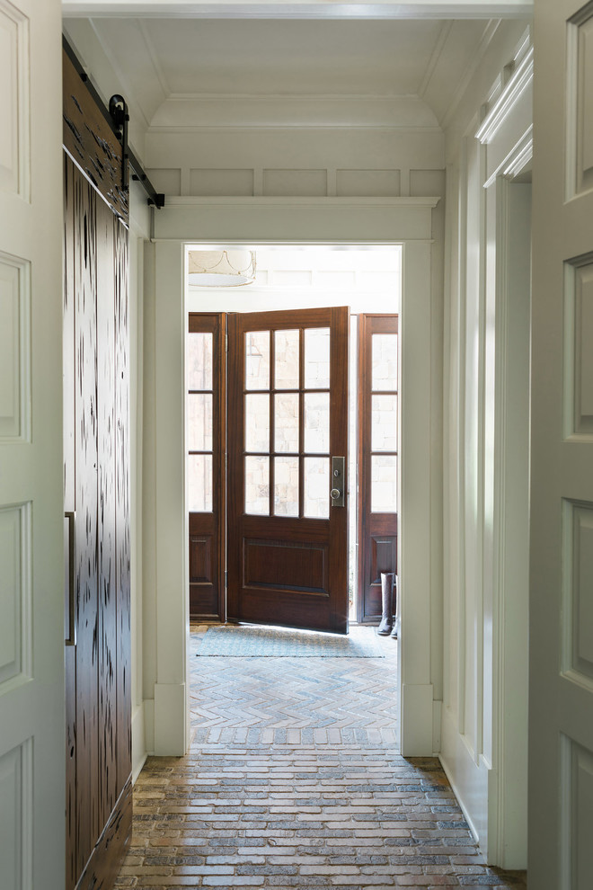 Foto di un corridoio stile marinaro di medie dimensioni con pareti bianche, pavimento in mattoni, una porta singola, una porta in legno scuro e pavimento marrone