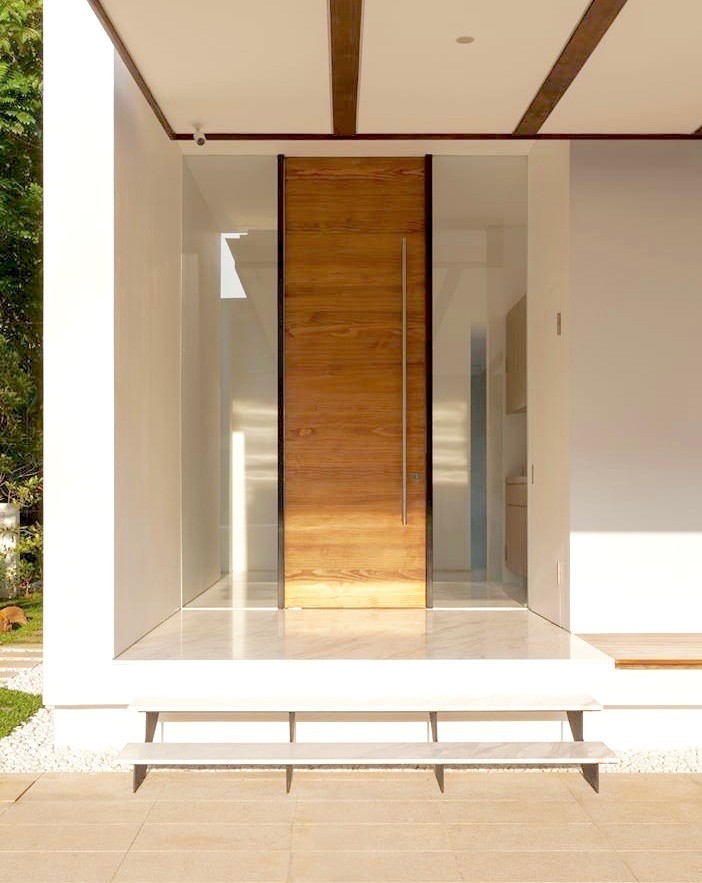 Imagen de puerta principal moderna grande con puerta pivotante, puerta de madera clara, paredes blancas, suelo de mármol y suelo blanco