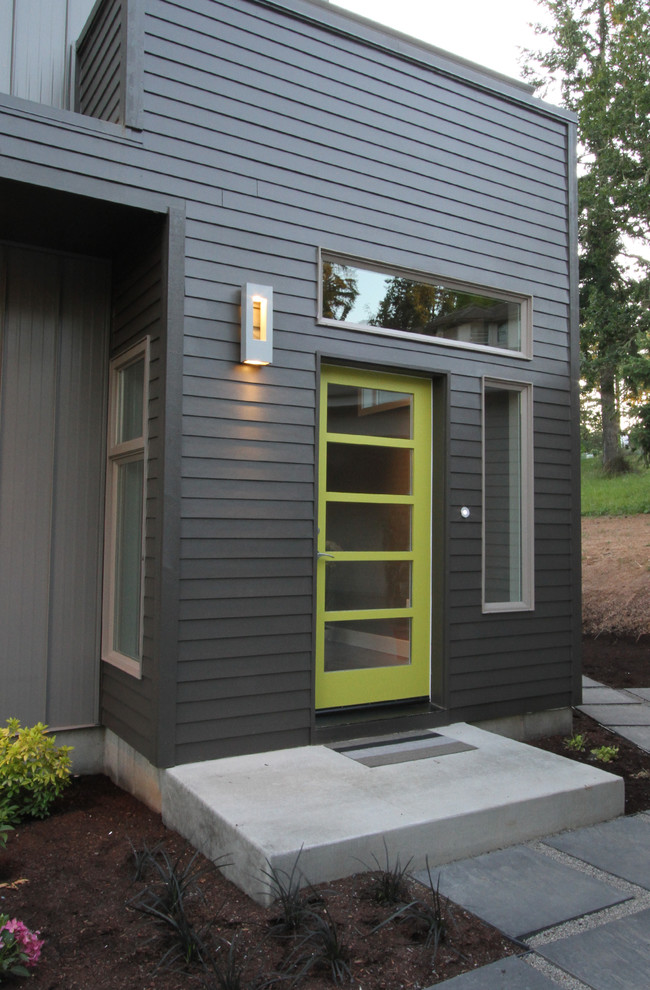 Réalisation d'une porte d'entrée design de taille moyenne avec un mur gris, un sol en bois brun, une porte simple et une porte verte.