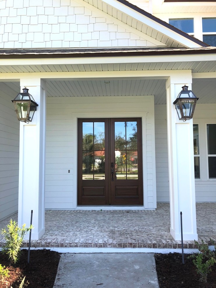 Immagine di una porta d'ingresso tradizionale con pareti bianche, pavimento in mattoni, una porta a due ante, una porta in legno scuro e pavimento multicolore