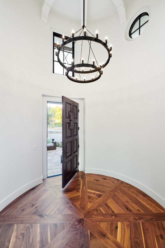Example of a mid-sized tuscan medium tone wood floor and brown floor entryway design in Orange County with white walls and a dark wood front door