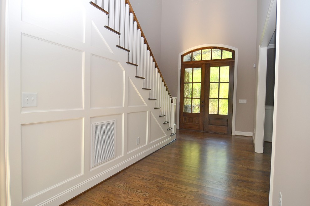 Immagine di una porta d'ingresso chic di medie dimensioni con pareti beige, pavimento in legno massello medio, una porta a due ante e una porta in vetro