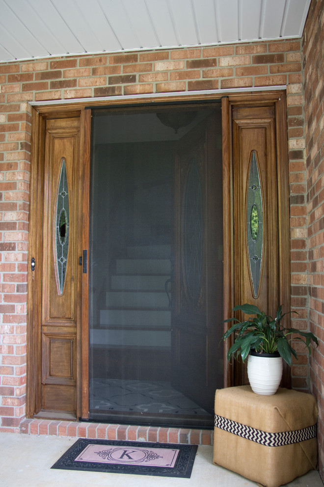 Cette image montre une petite porte d'entrée traditionnelle avec une porte simple et une porte en bois brun.