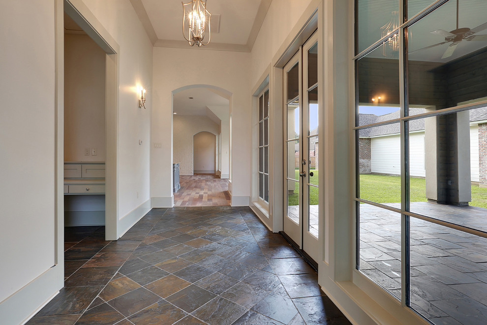 ニューオリンズにある高級な中くらいなトランジショナルスタイルのおしゃれな玄関ホール (白い壁、御影石の床、白いドア) の写真