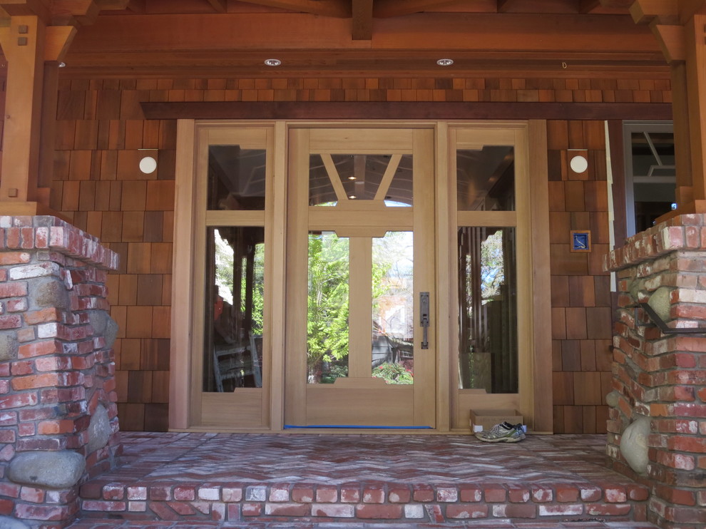 Entryway - huge craftsman brick floor entryway idea in Portland with a light wood front door