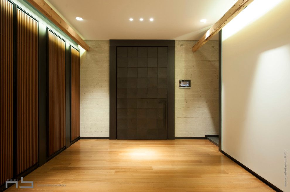 На фото: входная дверь среднего размера в стиле модернизм с белыми стенами, полом из фанеры, поворотной входной дверью и черной входной дверью с