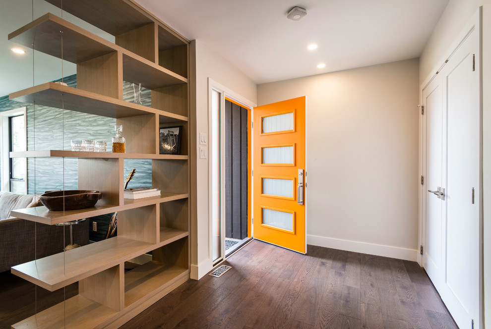 Aménagement d'une porte d'entrée contemporaine de taille moyenne avec un mur gris, un sol en bois brun, une porte simple et une porte orange.