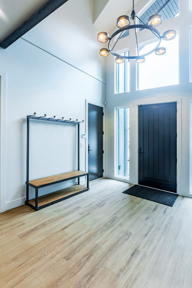 На фото: большое фойе в стиле модернизм с серебряными стенами, полом из винила, одностворчатой входной дверью, черной входной дверью и коричневым полом с