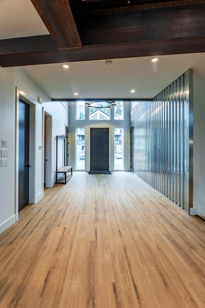 Idée de décoration pour un grand hall d'entrée minimaliste avec mur métallisé, un sol en vinyl, une porte simple, une porte noire et un sol marron.