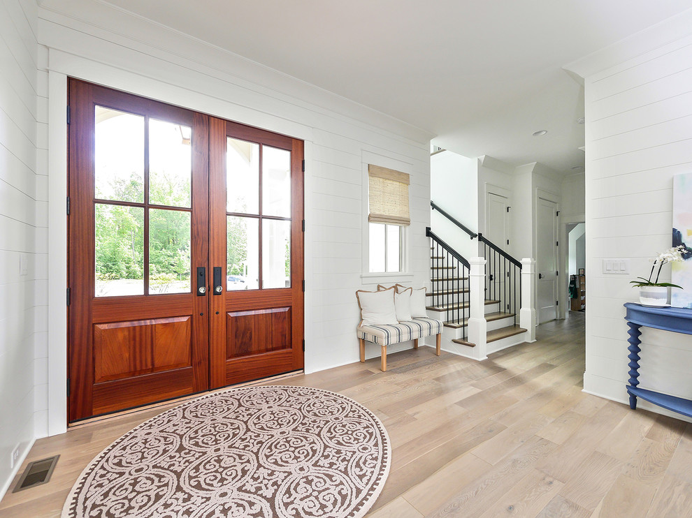 Example of a mid-sized farmhouse light wood floor and beige floor entryway design in Charlotte with white walls and a medium wood front door