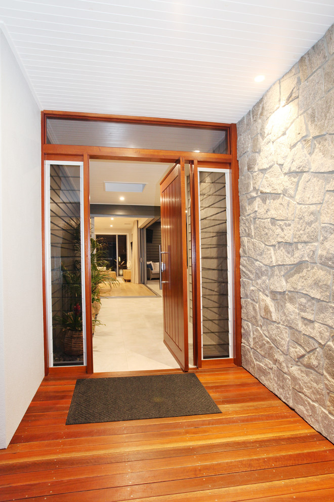 Réalisation d'une porte d'entrée design de taille moyenne avec un mur multicolore, un sol en bois brun, une porte pivot, une porte en bois brun et un sol blanc.