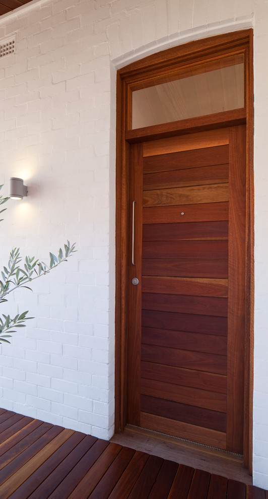 Cette photo montre une entrée tendance avec un mur blanc, une porte simple et une porte en bois brun.