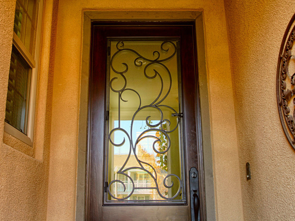 Ispirazione per una grande porta d'ingresso mediterranea con pareti arancioni, una porta singola e una porta in legno scuro