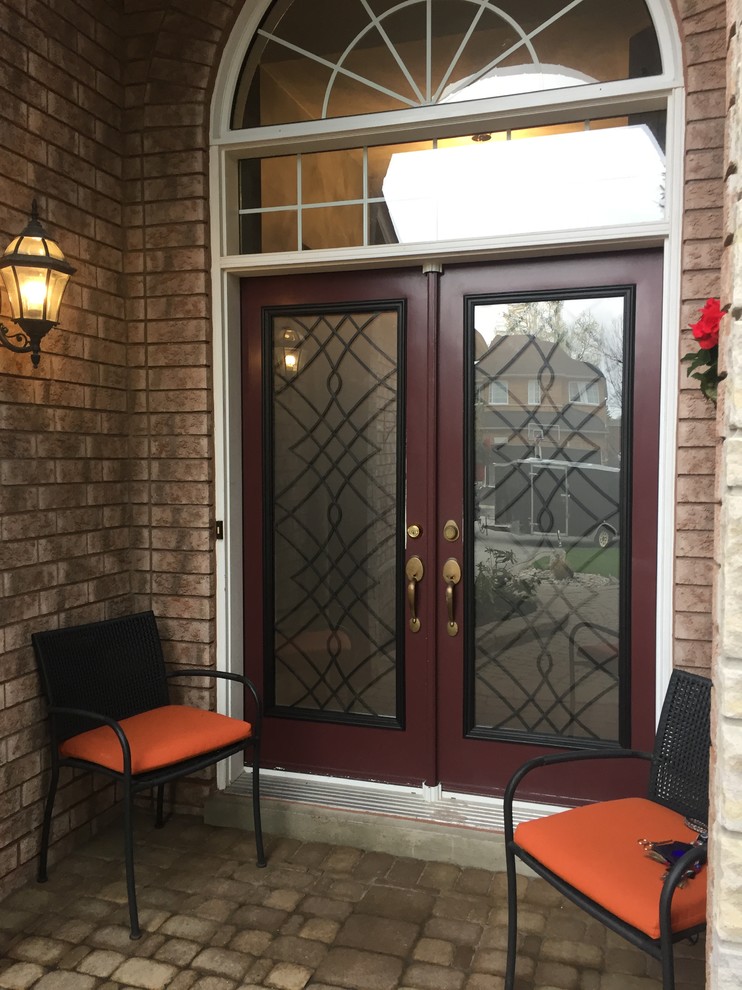 Imagen de puerta principal tradicional de tamaño medio con paredes marrones, suelo de cemento, puerta doble, puerta de vidrio y suelo marrón