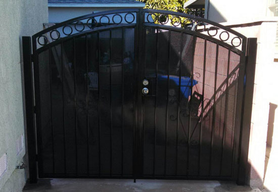 Cette image montre un jardin minimaliste avec un portail et une clôture en métal.