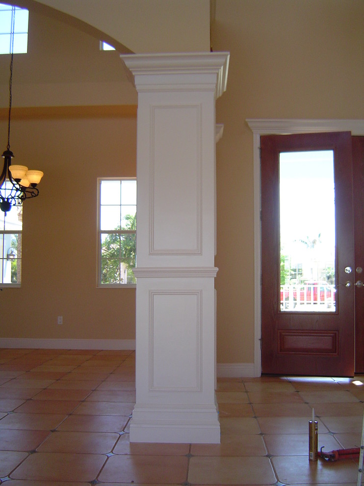 Inredning av en klassisk liten ingång och ytterdörr, med gula väggar, klinkergolv i keramik, en dubbeldörr, mellanmörk trädörr och beiget golv