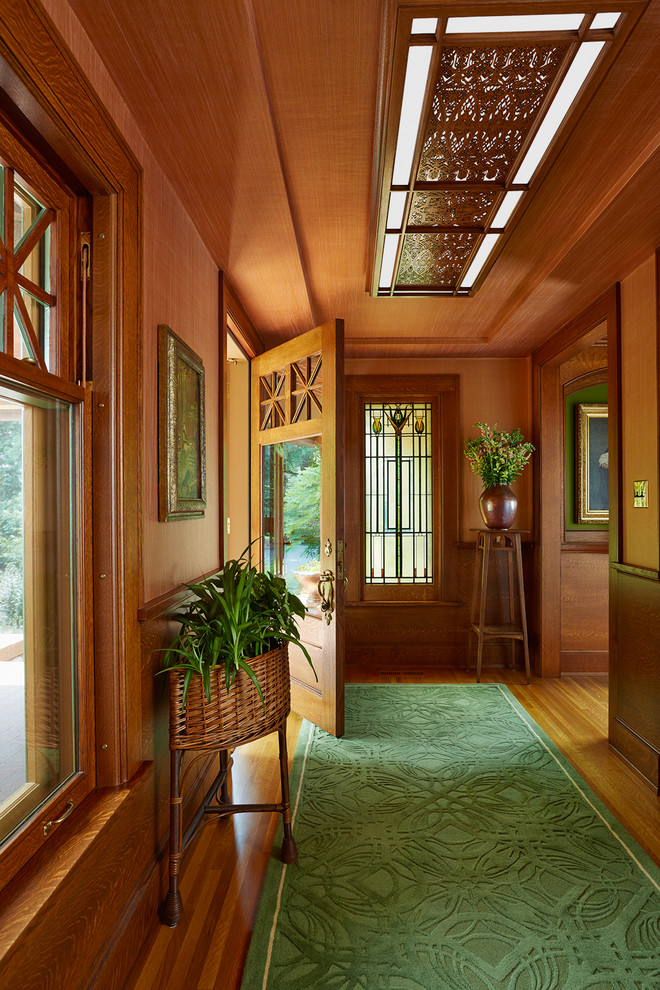 Cette image montre un hall d'entrée craftsman avec un sol en bois brun, une porte simple, une porte en bois brun et un mur marron.