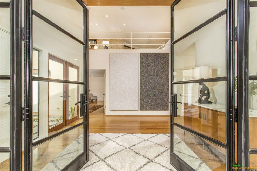На фото: большое фойе в стиле модернизм с белыми стенами, светлым паркетным полом, двустворчатой входной дверью, металлической входной дверью и коричневым полом