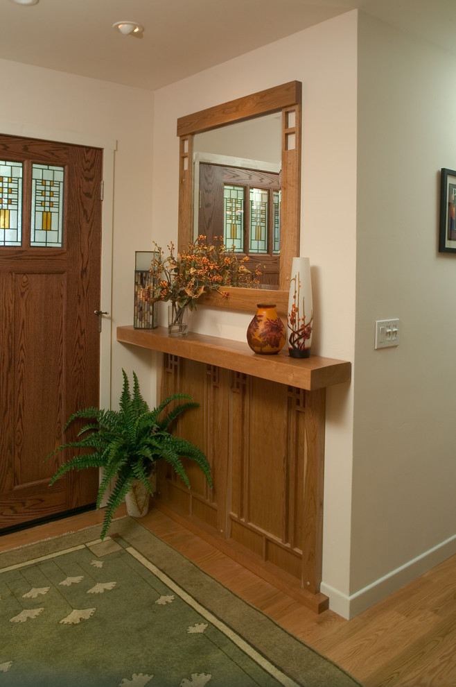 Aménagement d'une petite entrée craftsman avec un mur beige, parquet clair, une porte simple et une porte en bois brun.