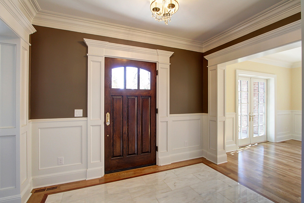 デンバーにある高級な広いトランジショナルスタイルのおしゃれな玄関ロビー (大理石の床、濃色木目調のドア、白い床、茶色い壁) の写真