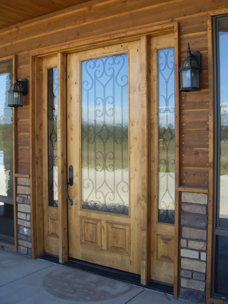 Réalisation d'une porte d'entrée chalet de taille moyenne avec un mur marron, sol en béton ciré, une porte simple, une porte en bois clair et un sol gris.