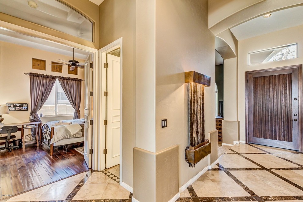 This is an example of a medium sized entrance in Phoenix with beige walls, a dark wood front door and beige floors.